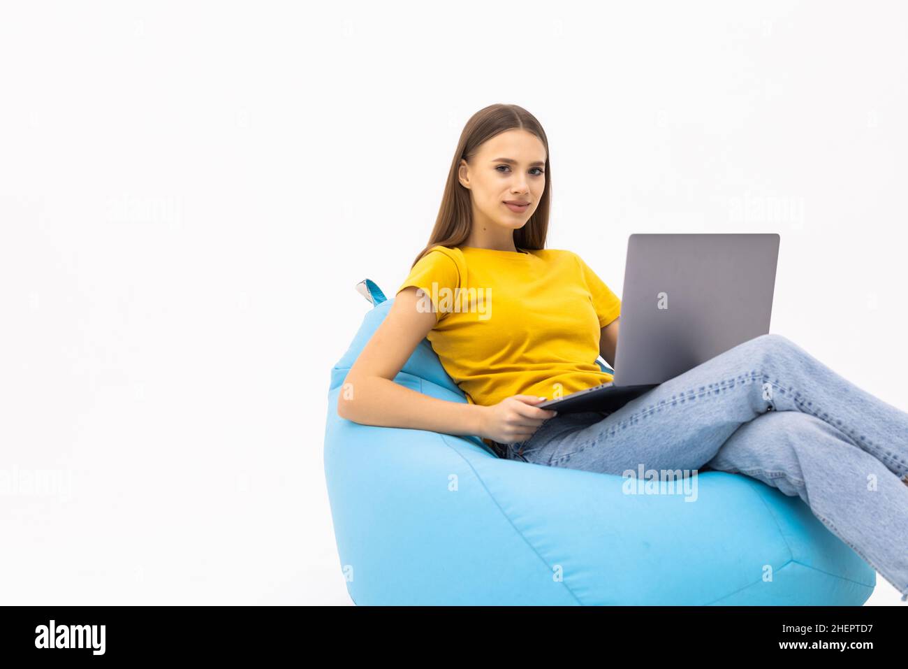 Junge Frau arbeitet an ihrem Computer Chat mit Start-up-Kunden sitzen große Tasche Lounge Stuhl tragen lässige Kleidung über weißen Hintergrund Stockfoto