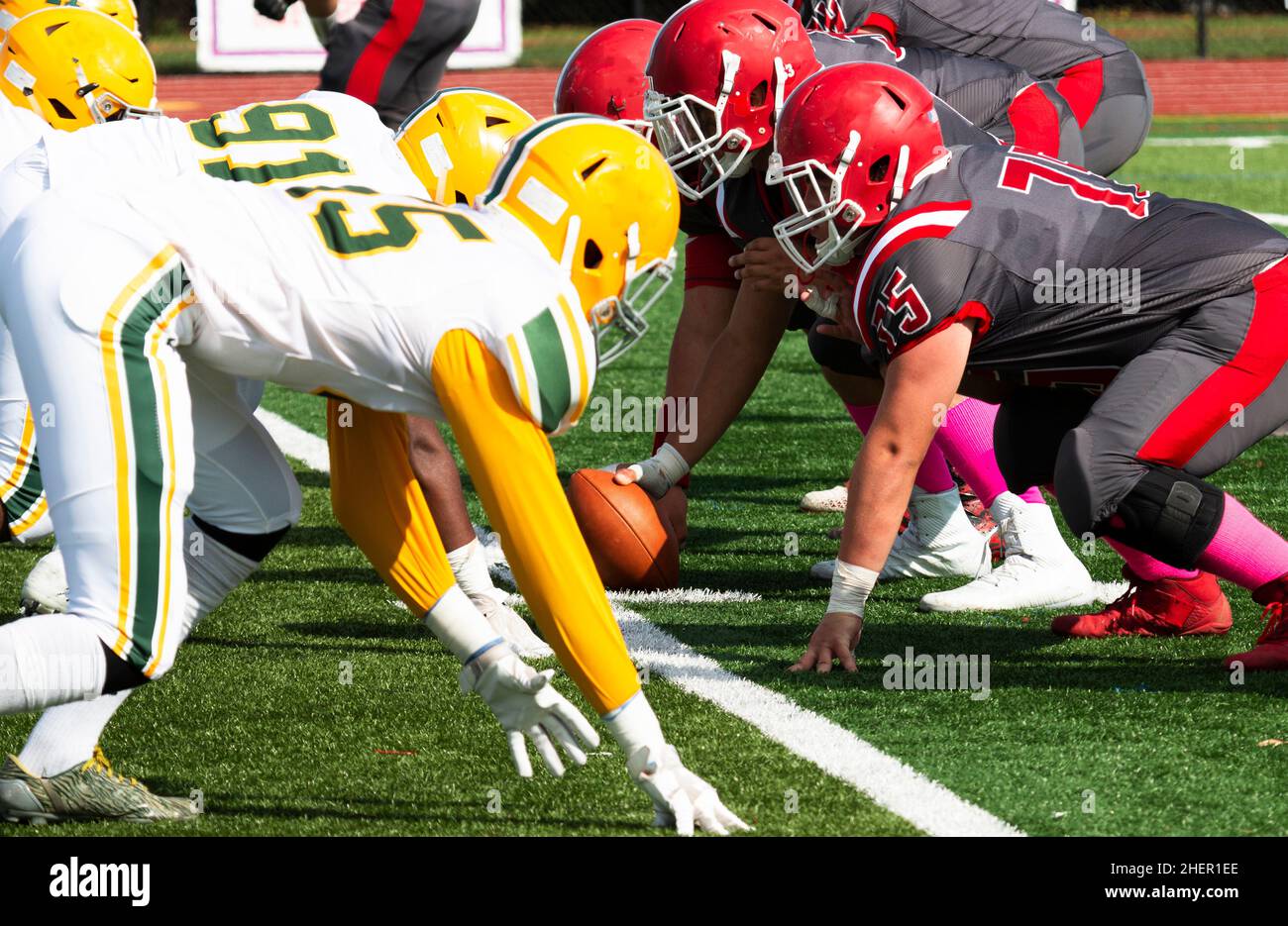 Zwei High School Teams sind aufgereiht, um ein Spiel während eines Spiels auf einem grünen Rasen zu starten. Stockfoto
