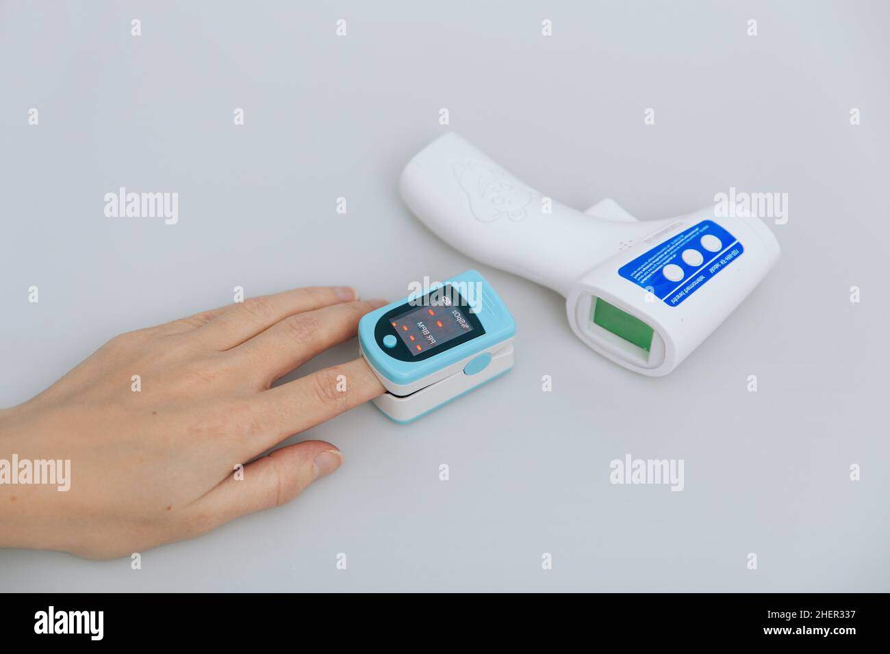 Pulsoximeter und Thermometerpistole auf weißem Hintergrund. Messung der Sauerstoffsättigung, der Pulsfrequenz und des Sauerstoffgehalts. Isometrisches Infrarot-Thermometer Stockfoto