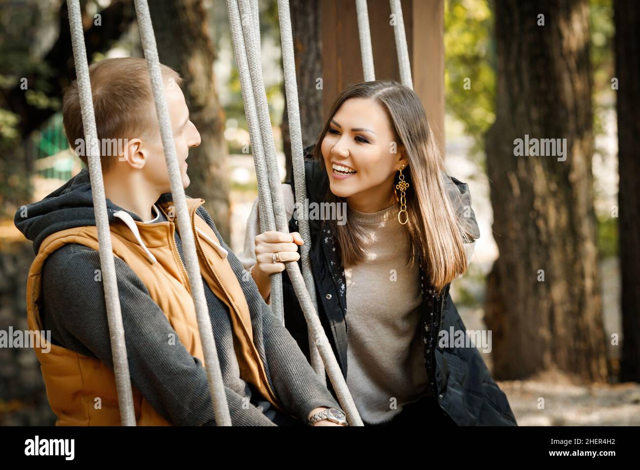Internationales glückliches Paar im Herbst im Park im Wald auf einer Schaukel. Hochwertige Fotos Stockfoto