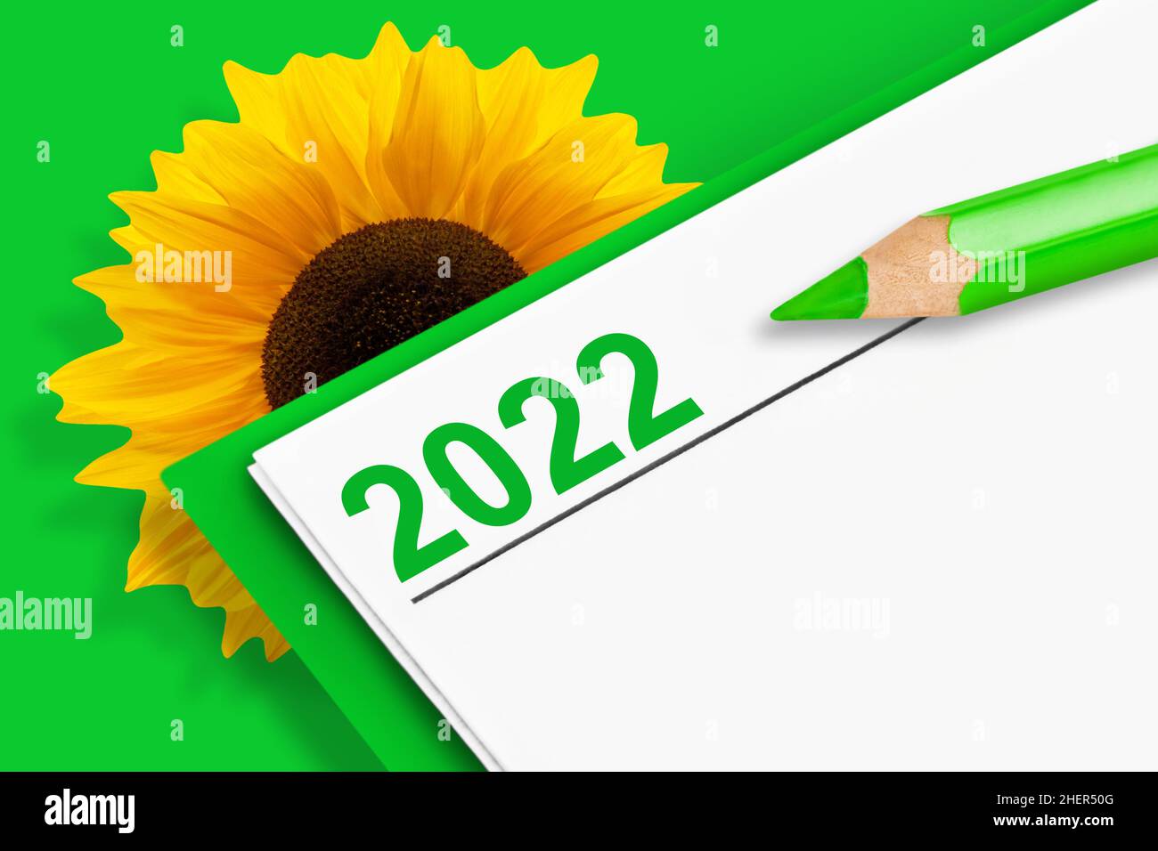 Kalender 2022 mit Sonnenblume und Bleistift auf grünem Hintergrund Stockfoto