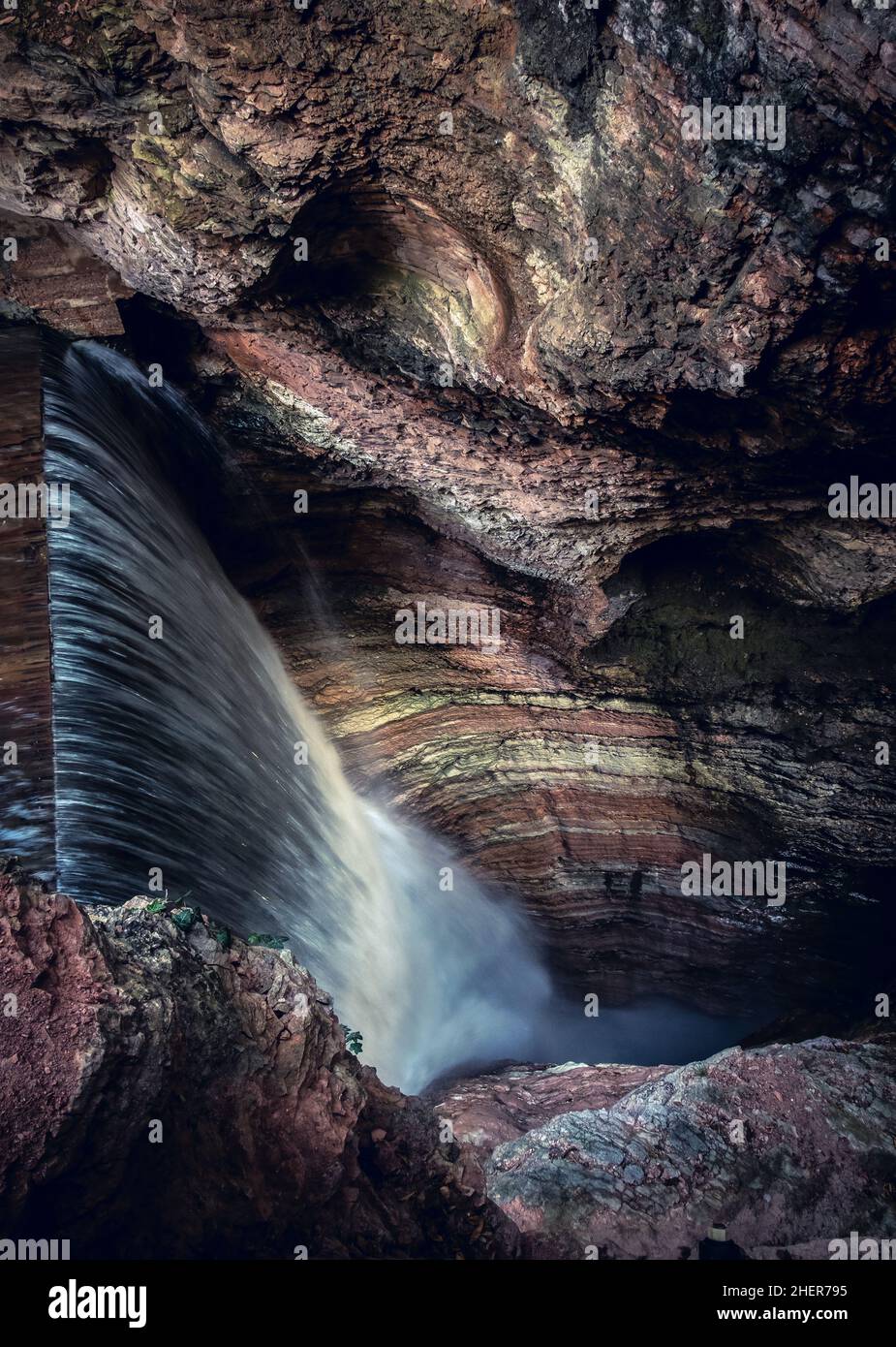 Wasserfallabfall in der engen und dunklen vertikalen Schlucht im Hintergrund Stockfoto