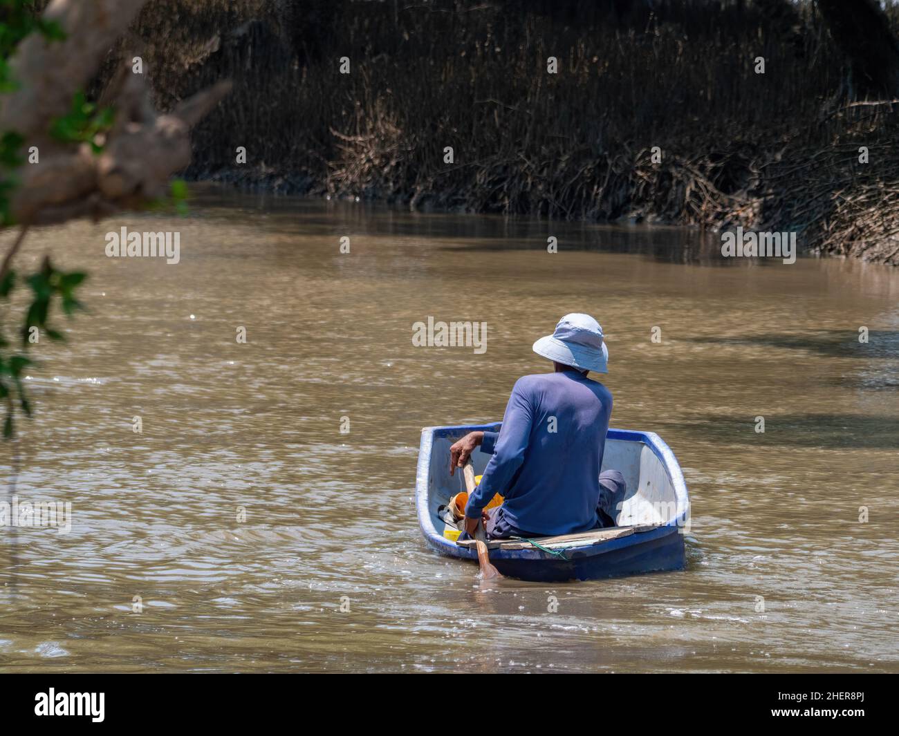 Mann paddelt in einem alten, verschlissenen Plastikjolle im Dorf Ban Si Long in der Provinz Samut Prakan in Thailand entlang eines Kanals. Stockfoto