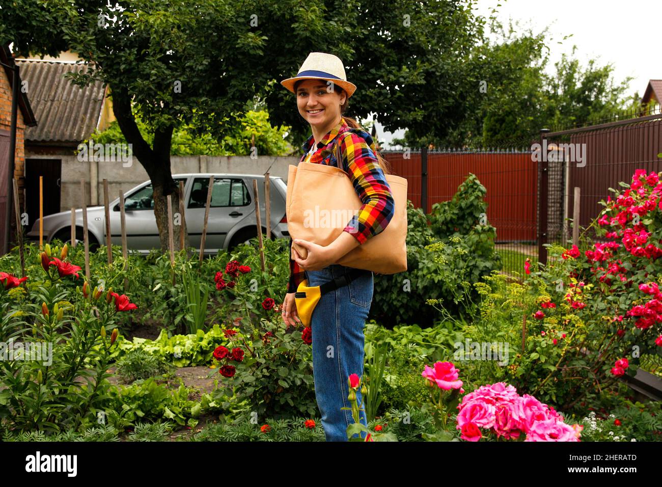 Junge Frau mit Öko-Tragetasche oder Shopper auf der Schulter und lächelnd. Öko-Beutel, Kunststoff stoppen. Natur Sommer Hintergrund, Hinterhof. Stofftasche aus Baumwolle Stockfoto