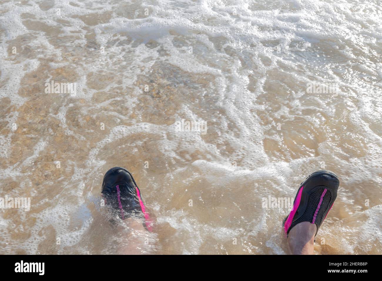 Schöne Nahaufnahme der Schaumstoffwelle auf den Herrenfüßen in Badeschuhen.  Griechenland Stockfotografie - Alamy