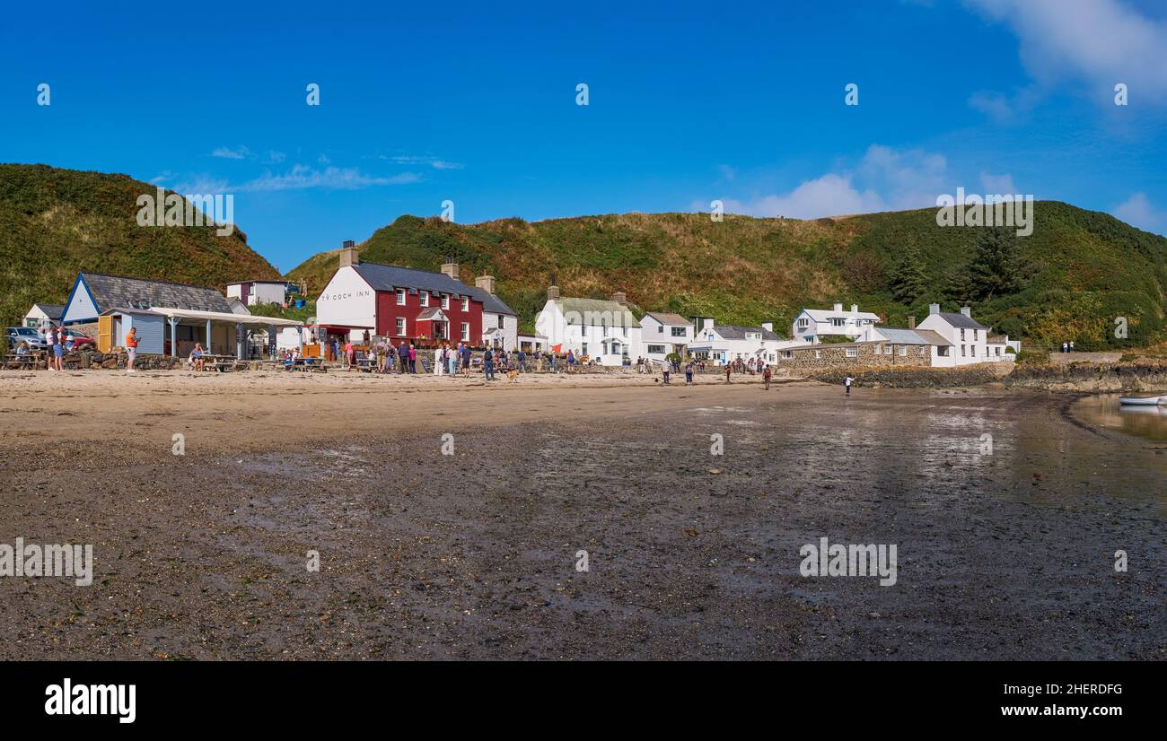 Touristen versammeln sich vor dem Ty Coch Inn am Strand im Dorf Porth Dinllaen, Nordwales Stockfoto