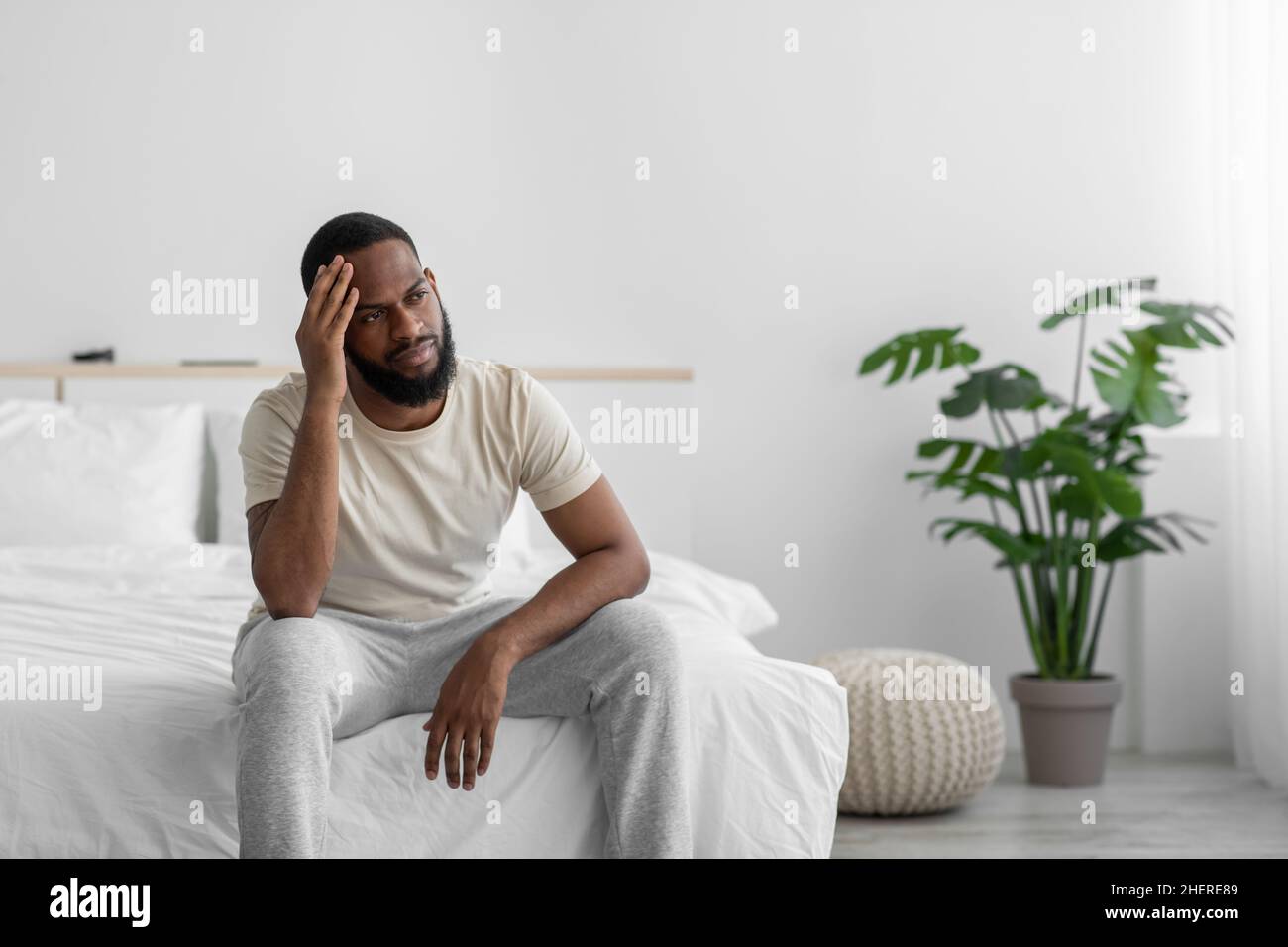 Verzweifelter junger afroamerikaner mit Bart leidet unter Einsamkeit, Depressionen im Schlafraum Stockfoto