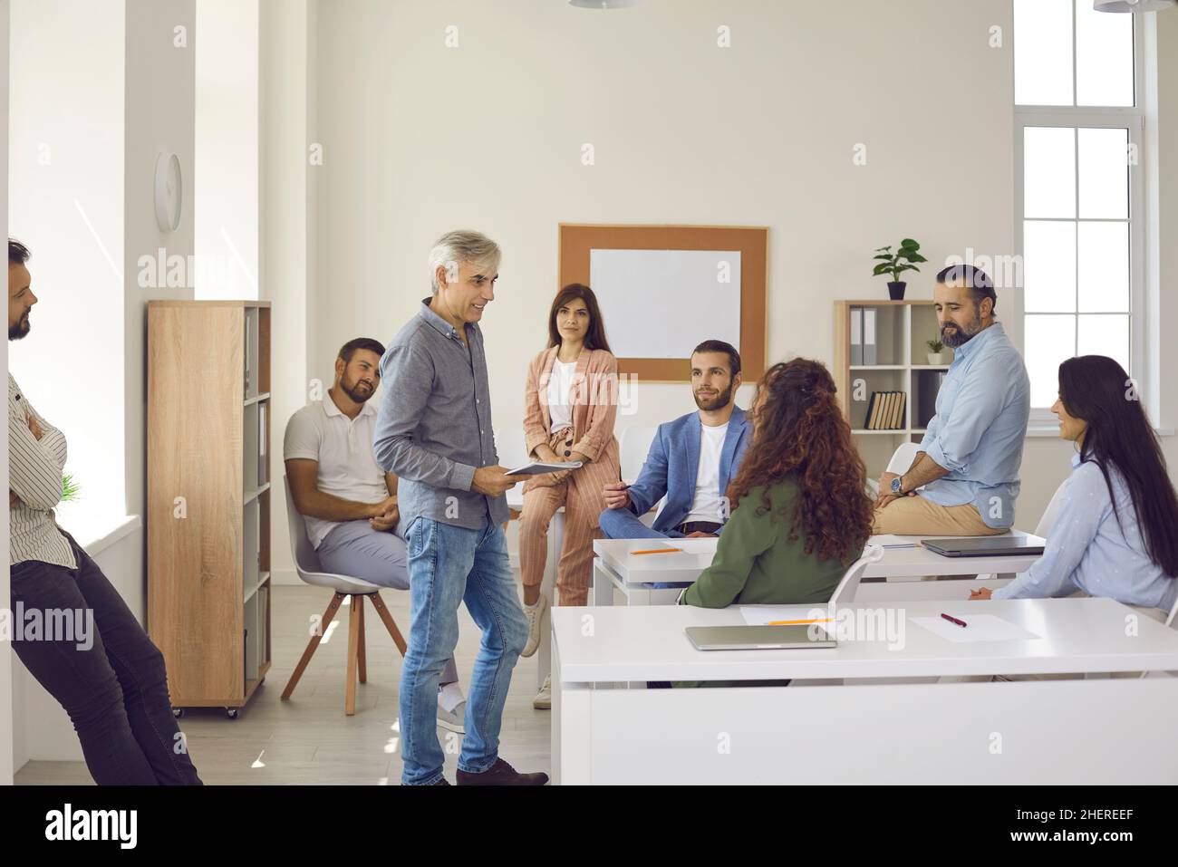 Gruppe von Personen, die während der Geschäftsschulung im Klassenzimmer oder Büro dem Coach zuhören Stockfoto