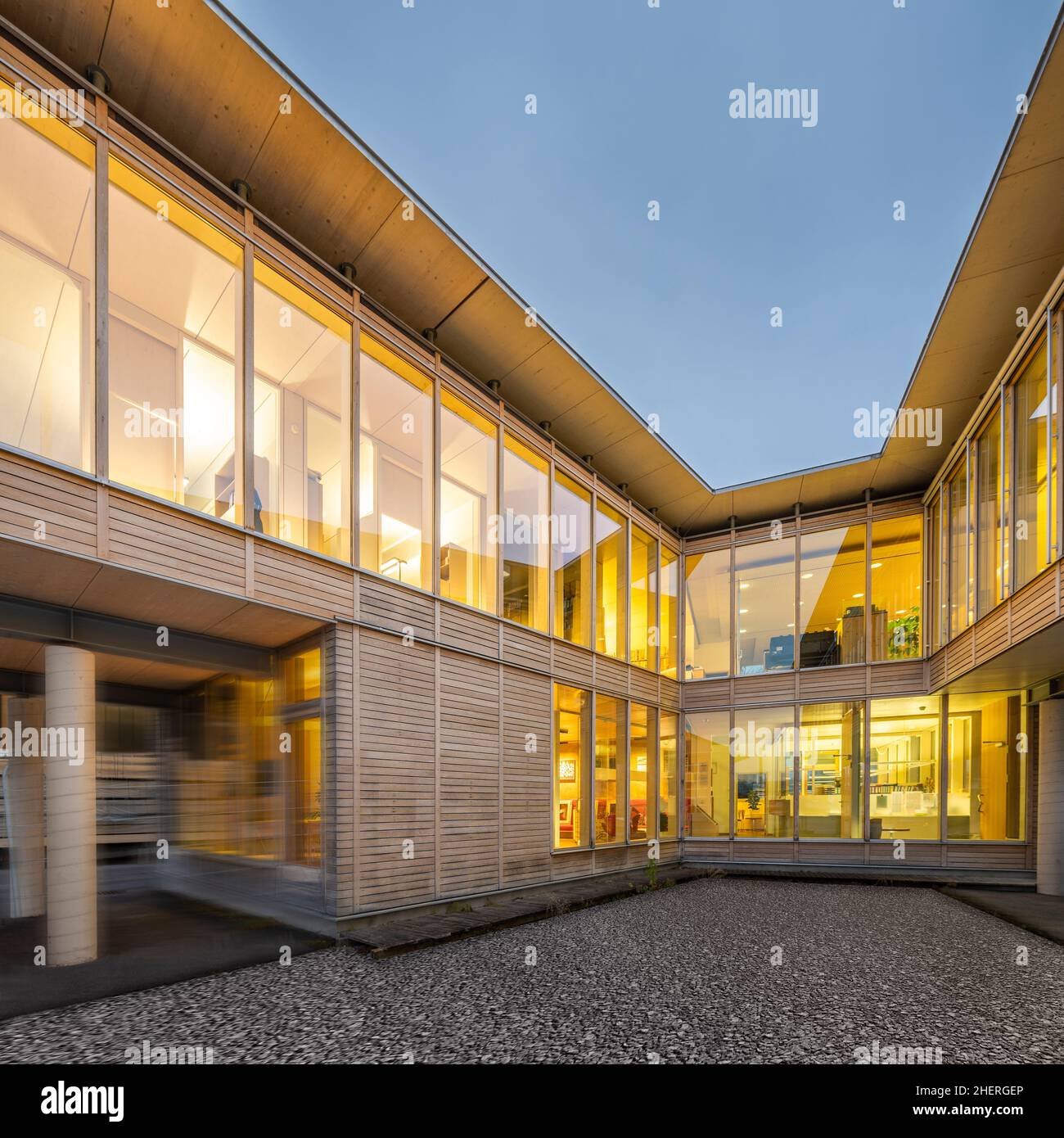 Blick auf die zwei Beine eines nachhaltigen Holz-Bürogebäudes vom Innenhof aus mit nächtlicher Beleuchtung Stockfoto