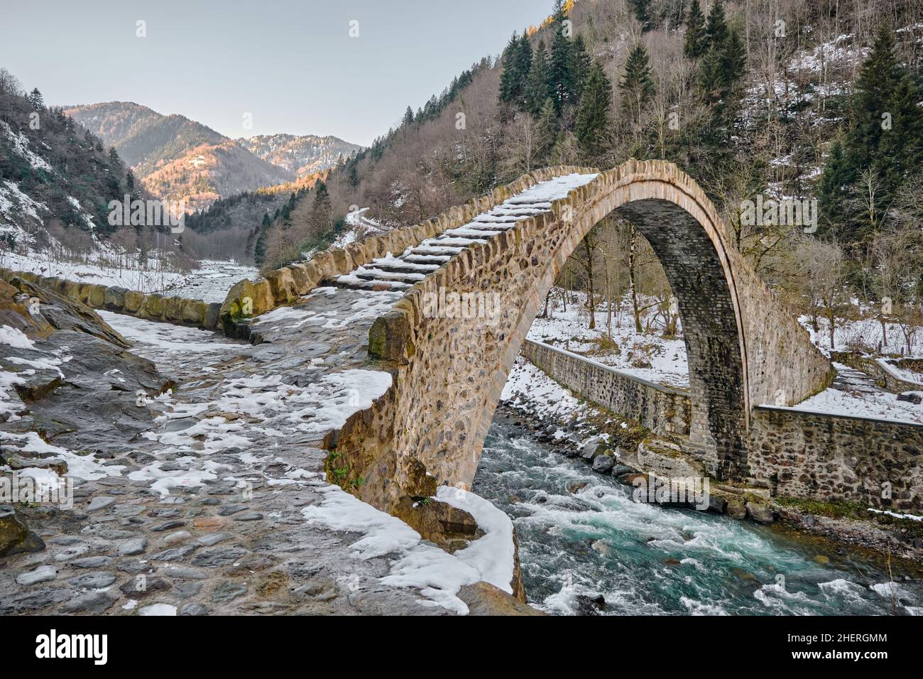 Steinbrücke bei trabzon im Winter, Fluss fließen unter der Steinbrücke und riesigen Berg Hintergrund. Winter Konzept Schnee. Stockfoto