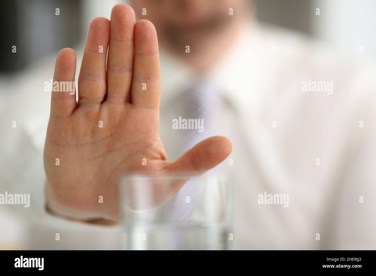 Männliche Hand zeigt eine negative Geste zum Glasbecher Stockfoto
