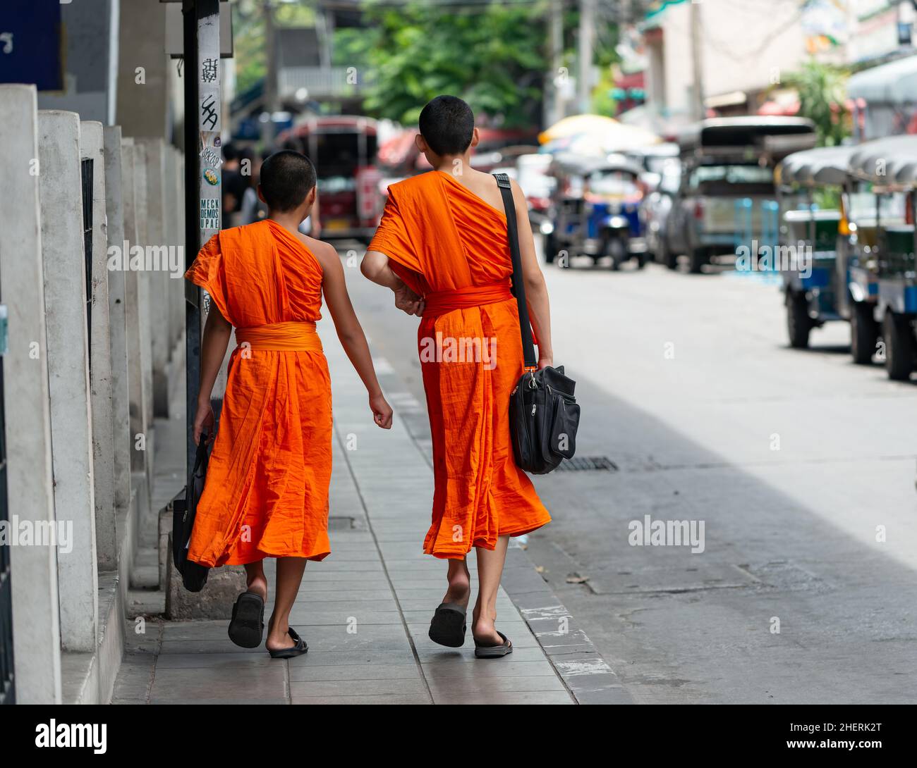 Zwei junge Mönche, die in Bangkok eine Straße entlang gehen. Rückansicht. Stockfoto