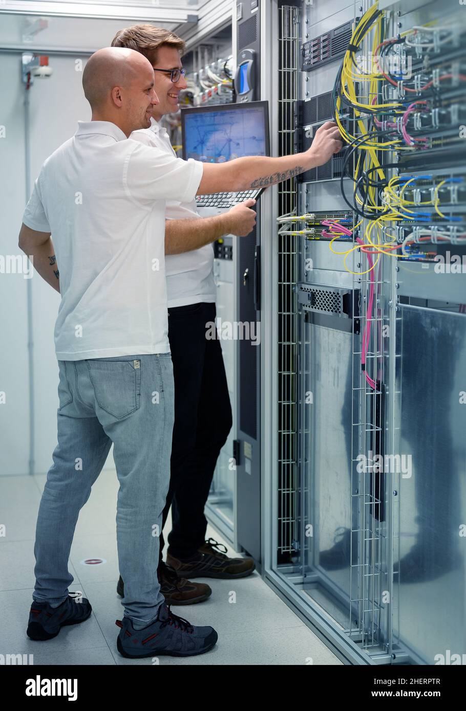 Zwei IT-Experten mit Notebook im Serverrechenzentrum, die ein Problem lösen Stockfoto