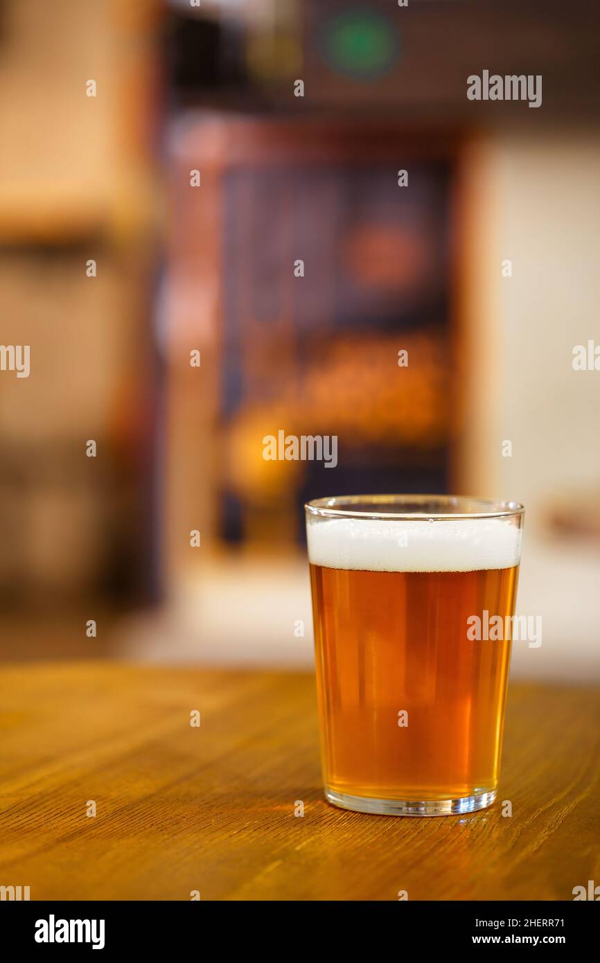 Ein Glas köstliches Craft-Bier vom Fass auf einem Holztisch. Pint goldenes indisches Pale Ale IPA Stockfoto