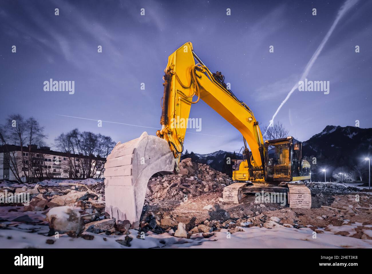 Riesige orangefarbene Schaufelgrubber auf Abbruchstelle in der Nacht Stockfoto