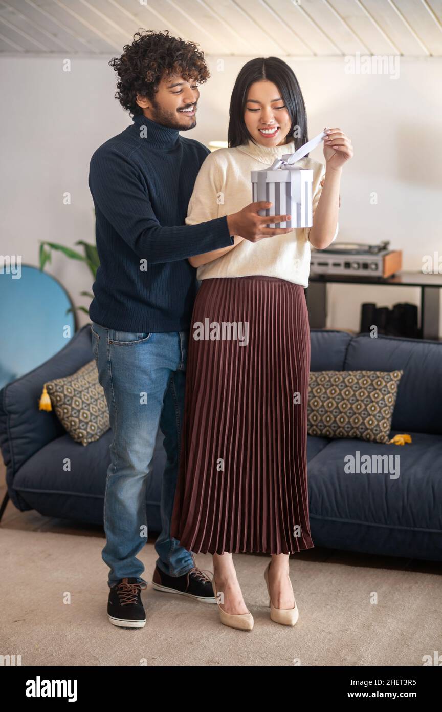Mann, der lächelnde Frau, die drinnen steht, beschenkt Stockfoto