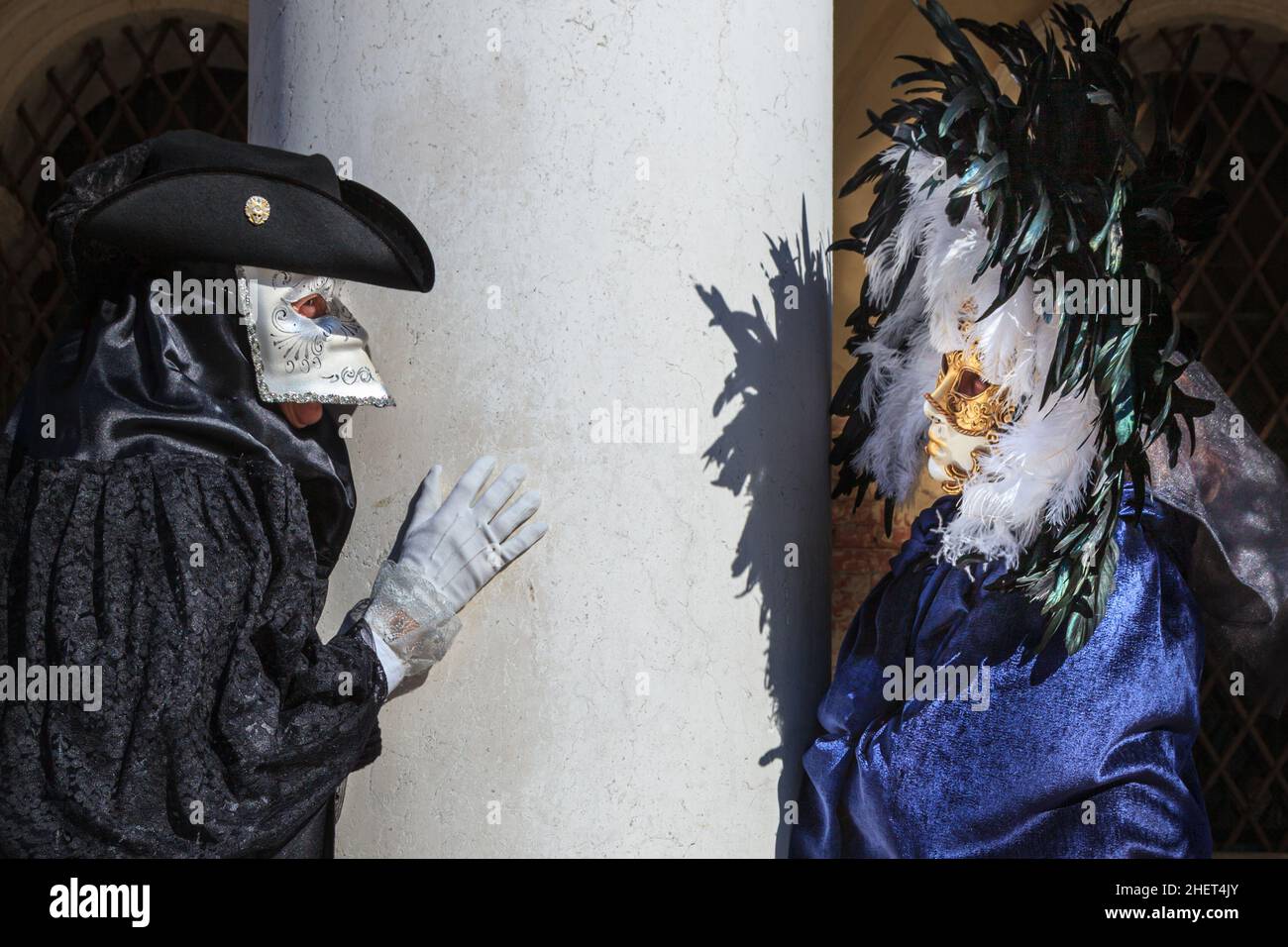 Mann im historischen bauta Kostüm, Tabarro Mantel und weiße Larvenmaske, Frau in Feder und Goldmaske, Karneval von Venedig, Karneval von Venedig, Venetien, Ita Stockfoto