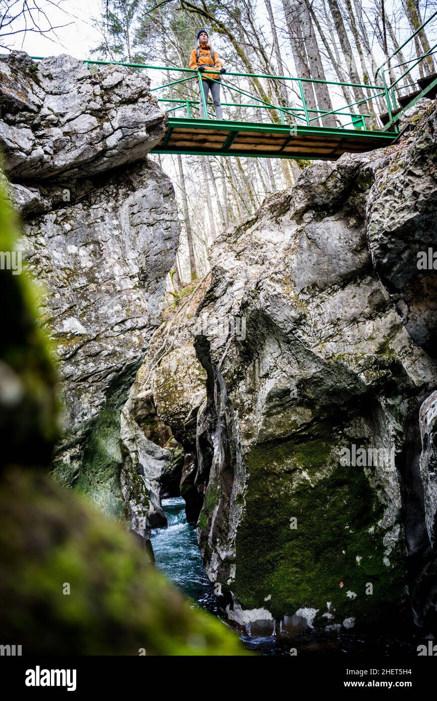 Frauen mit gelber Jacke stehen auf der Brücke über die Schlucht der Mostnica-Schlucht bei Bohinj, Slowenien Stockfoto