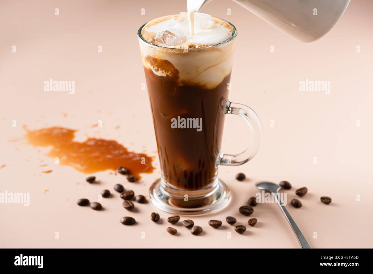 Milch in Eiskaffee gießen, erfrischendes, sommerliches kaltes Kaffeegetränk Stockfoto