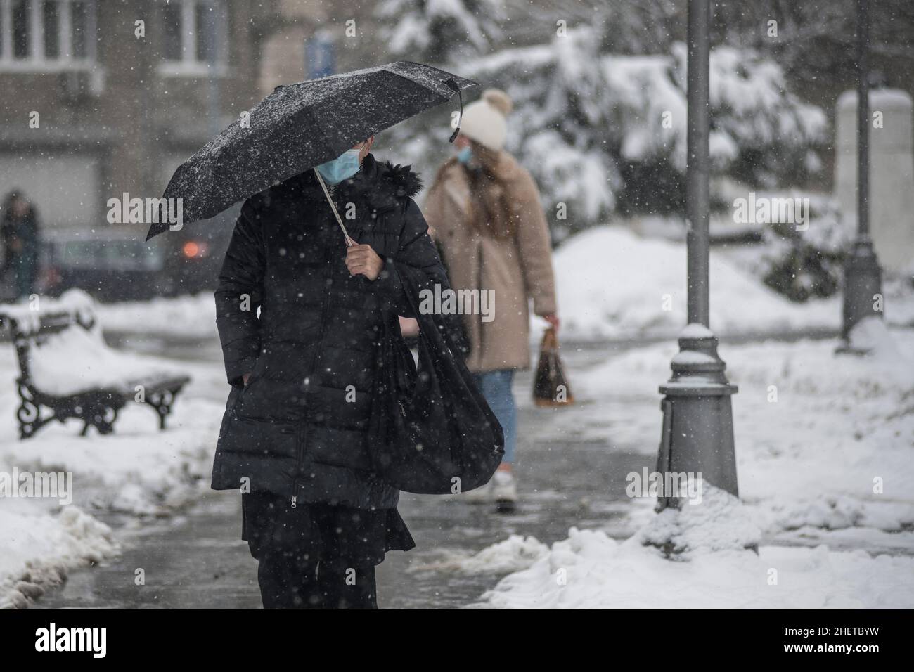 Winter in Serbien: Mann mit Regenschirm und Gesichtsmaske im Saint Sava Park, Belgrad Stockfoto