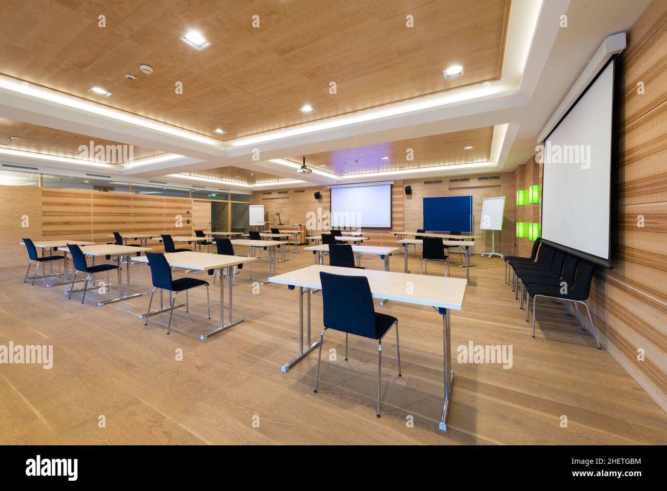 Moderner Konferenzraum aus Holz mit Tischen, Stühlen und Projektionsleinwand Stockfoto