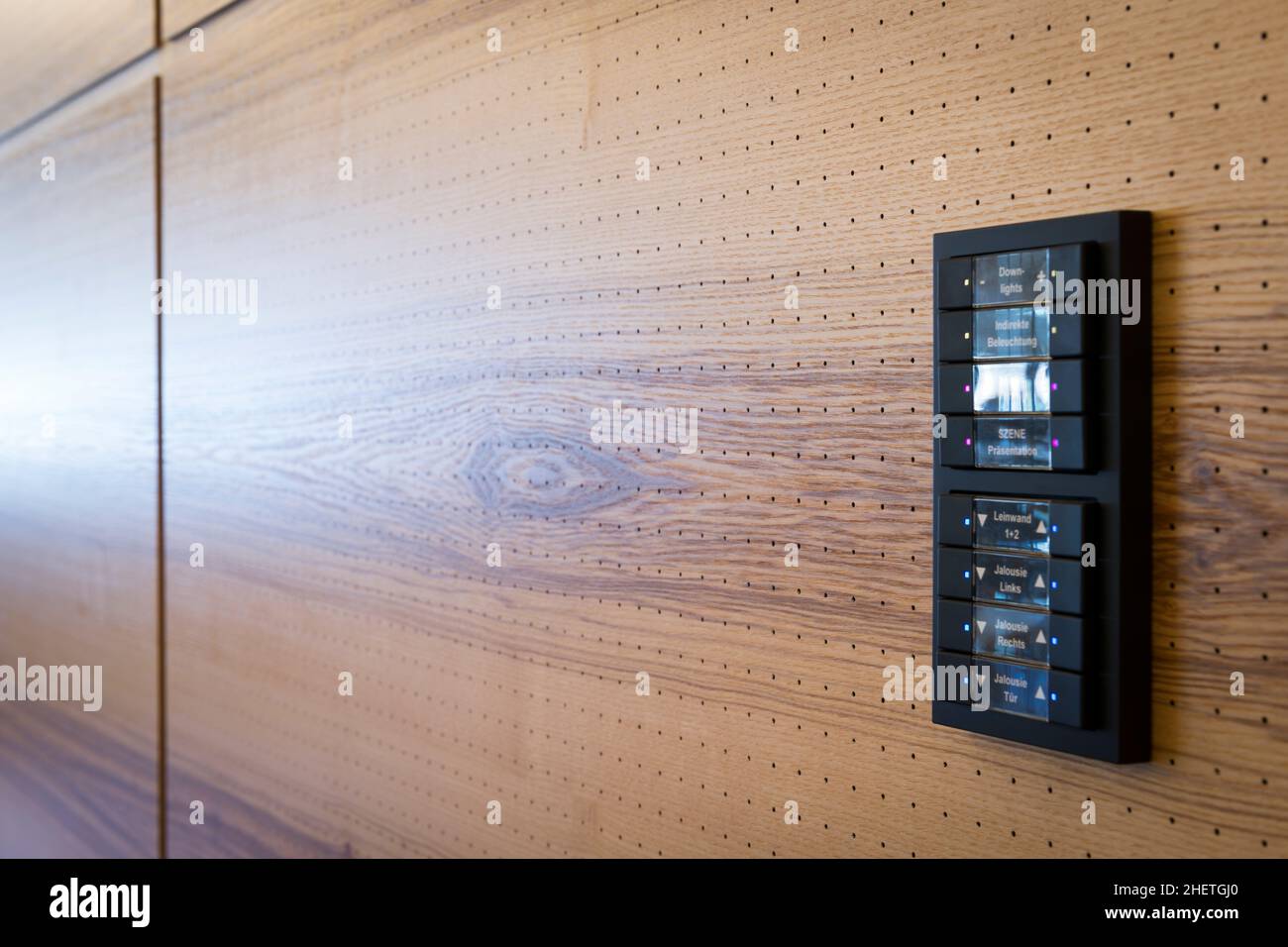 Schwarze Schalter zur Lichtsteuerung an hölzernen Akustikwänden Stockfoto