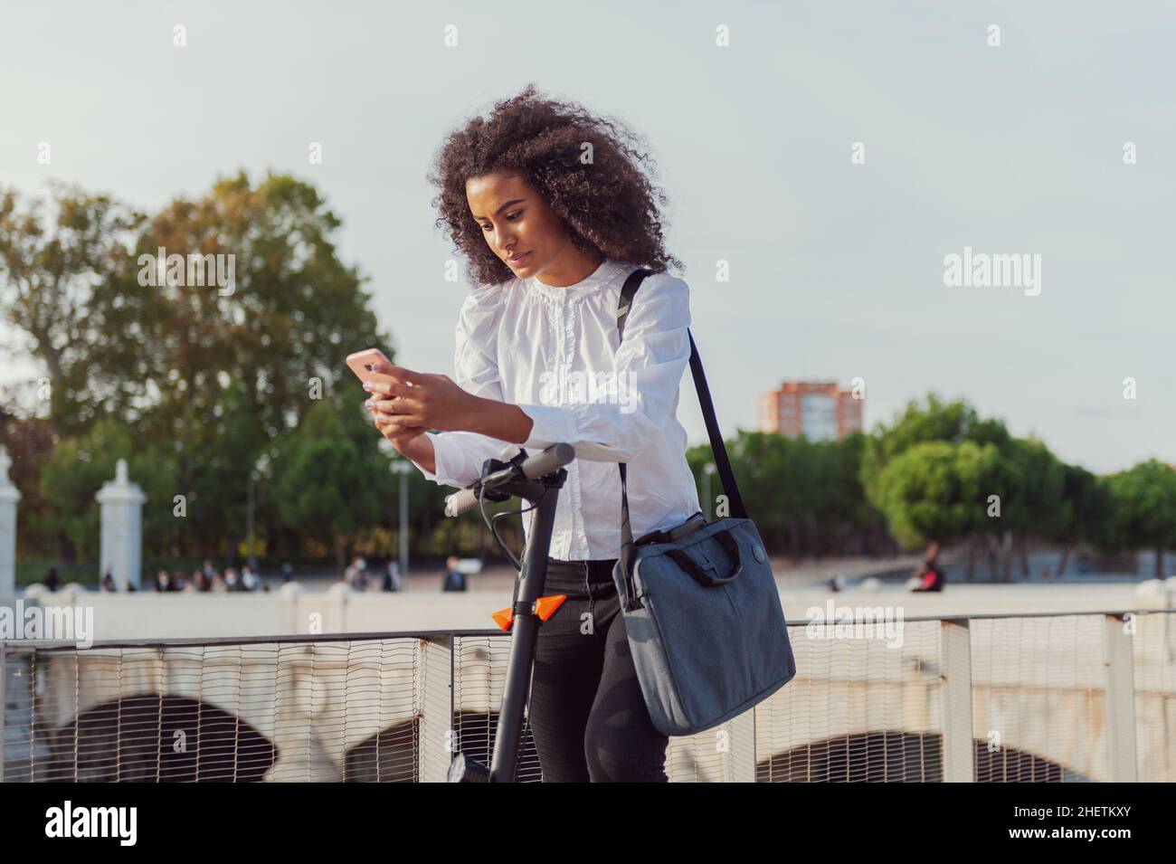 Junge Frau lädt die App, um den Elektroroller zu verwenden In der Stadt Straße gesund Lebensstil nachhaltigen Lebensstil Stockfoto