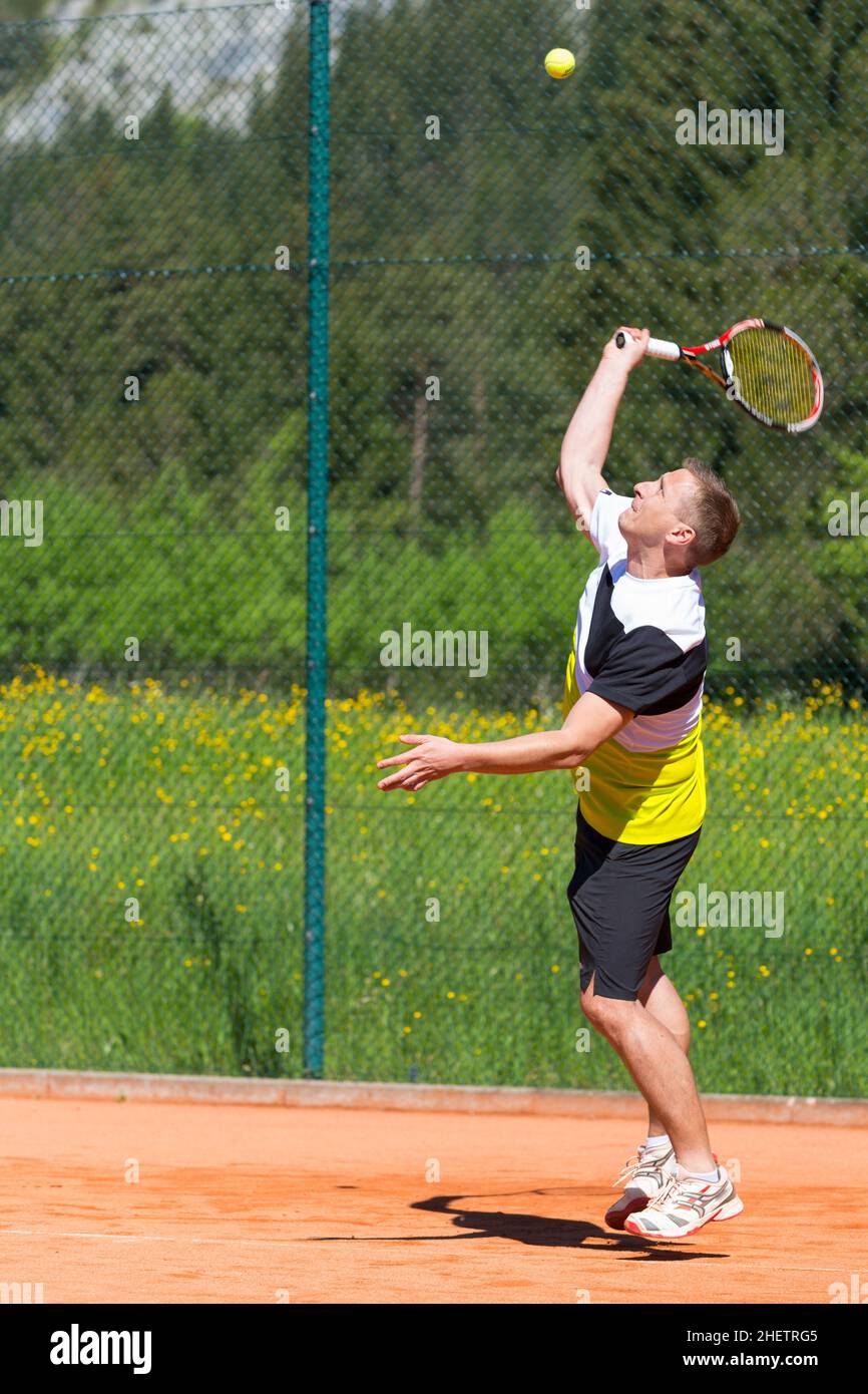 Der männliche Tennisspieler trifft den Serviceball Stockfoto