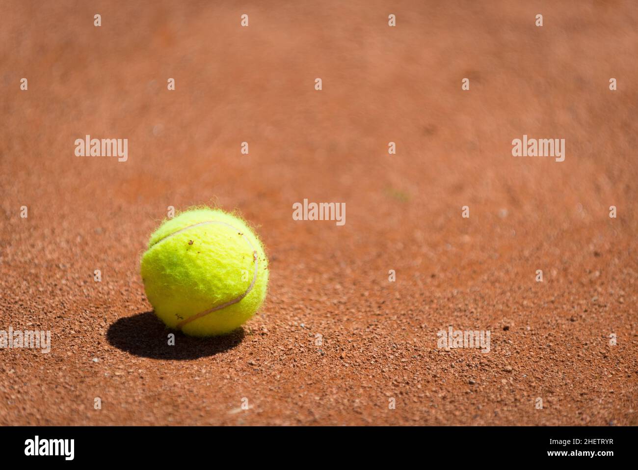 Gelber Tennisball auf orangefarbenem Sand Stockfoto