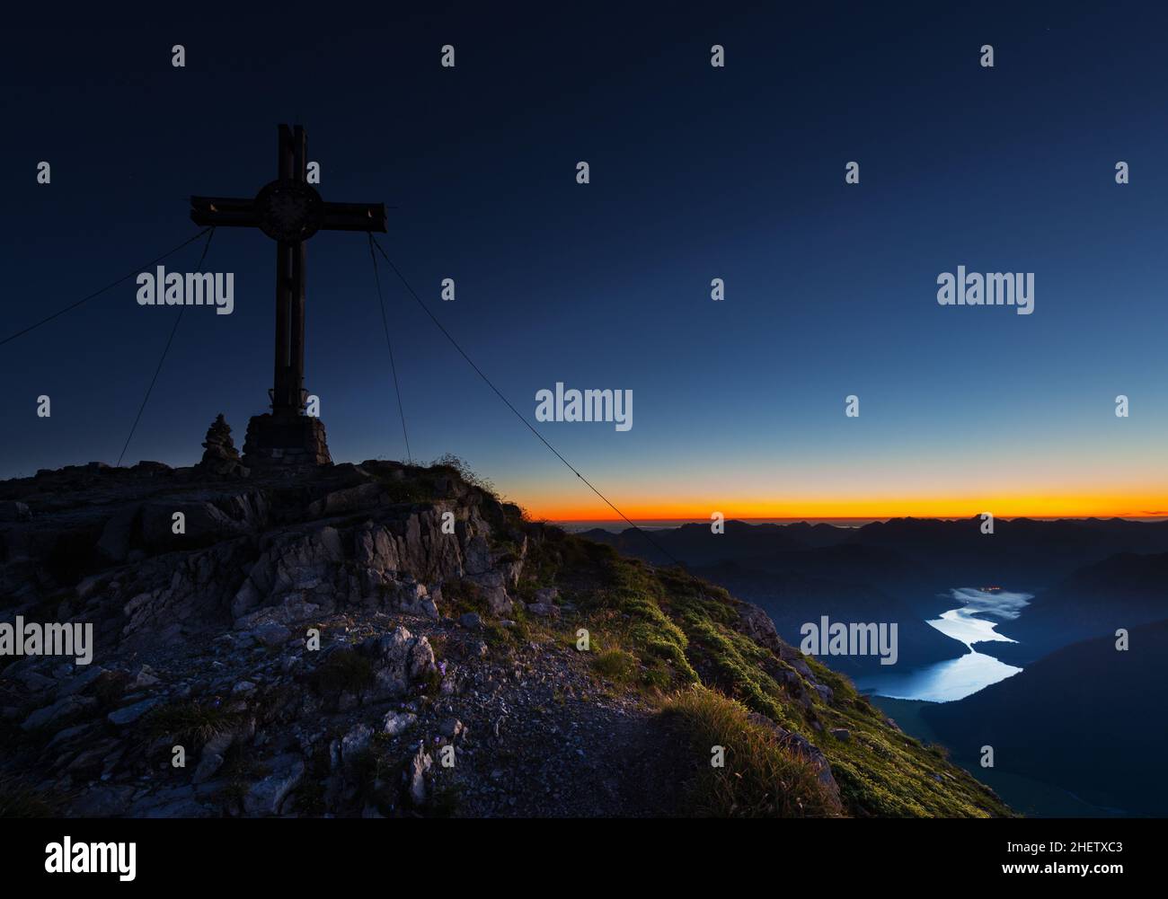 sonnenaufgangslandschaft mit leuchtendem Horizont und Gipfelkreuz Stockfoto