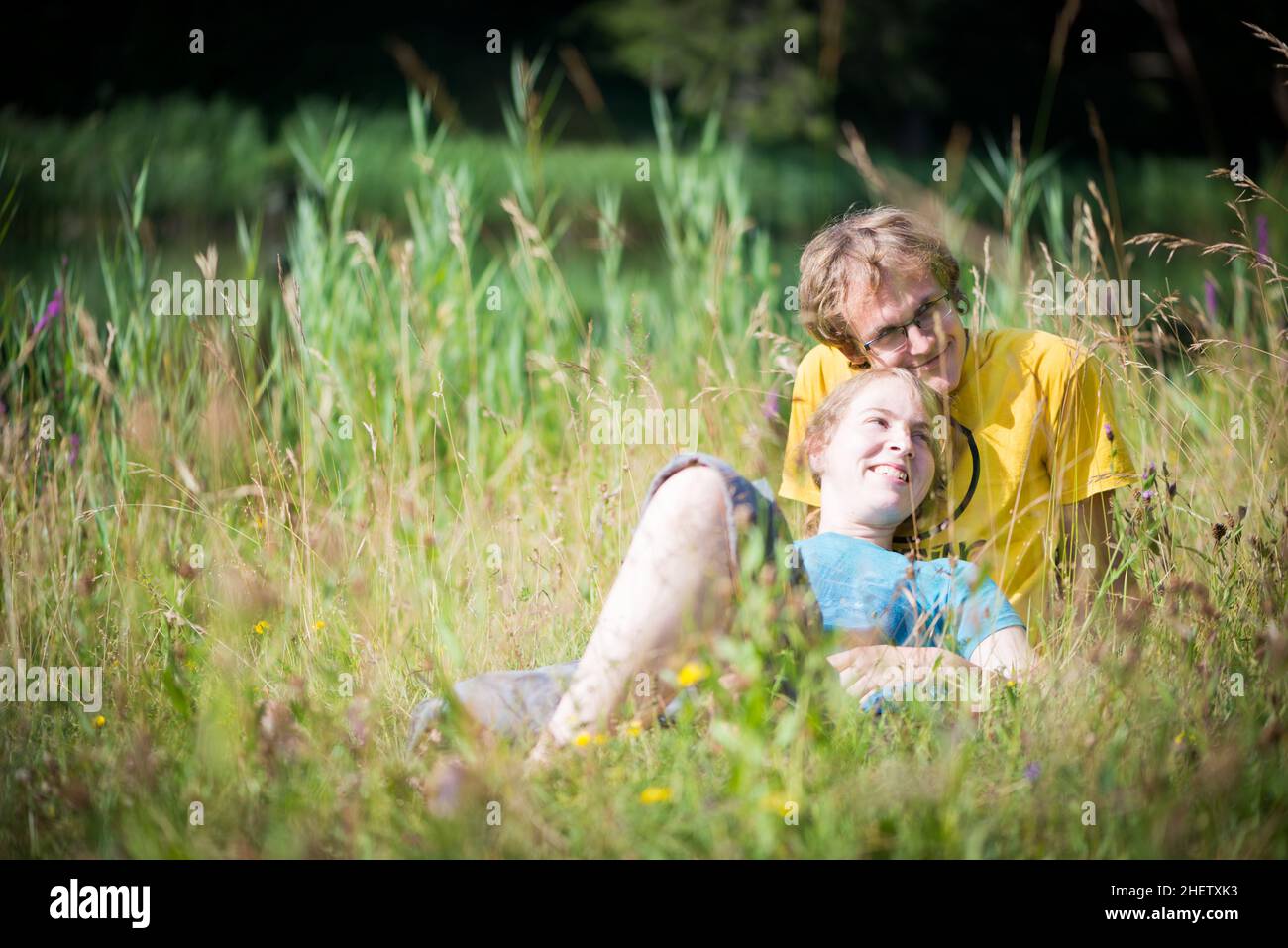 Junge schöne Paar im hohen Gras liegen Spaß im Sommer Stockfoto