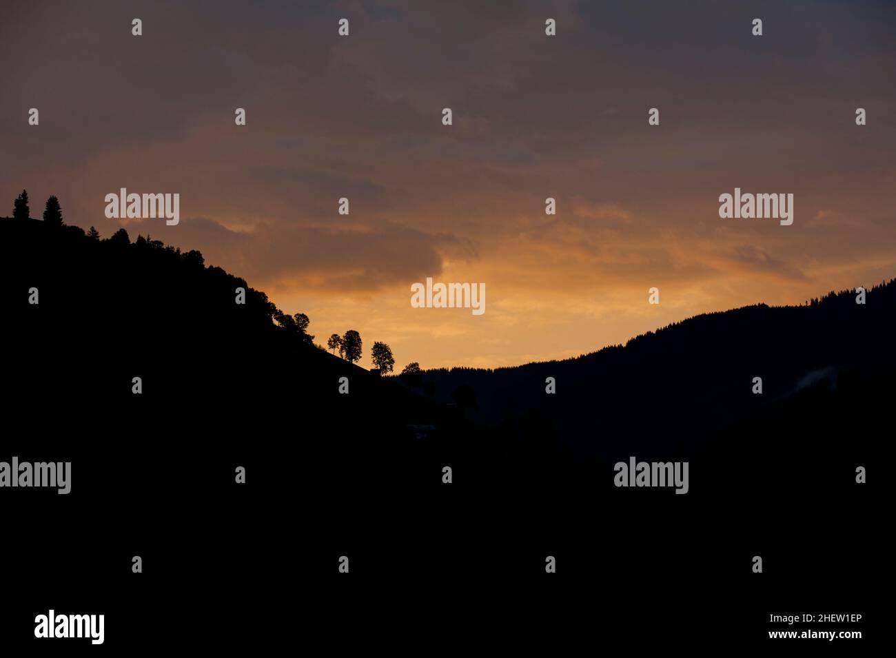 Silhouette eines Berges oder Hügels mit Umriss von Bäumen am orangefarbenen Himmel Stockfoto