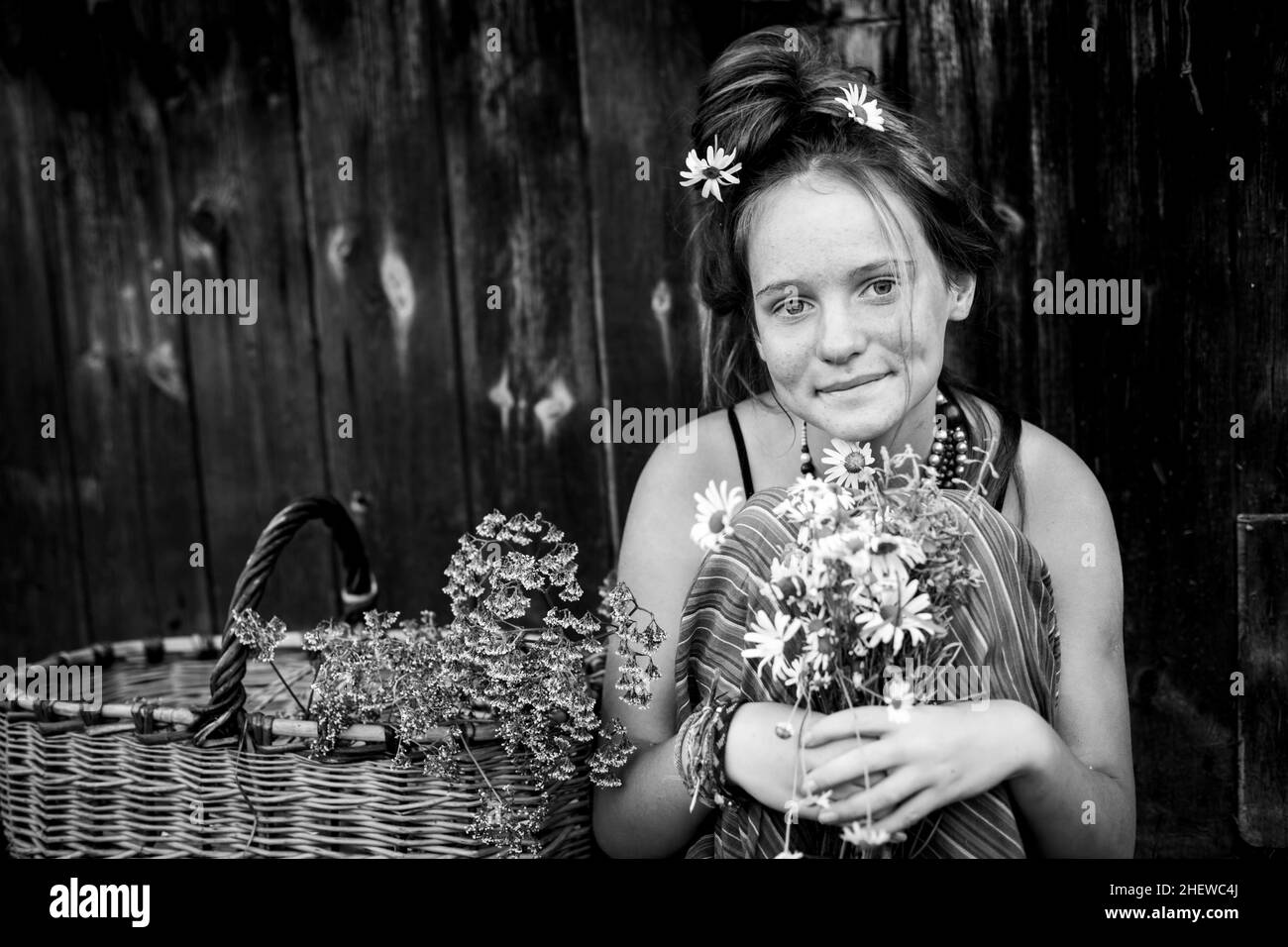 Ein Mädchen mit Gänseblümchen und einem Korb. Schwarzweiß-Foto. Stockfoto