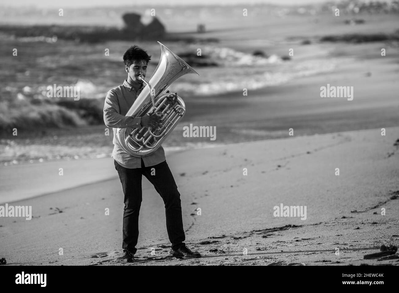 Ein Musiker, der eine Tuba auf dem Meer spielt. Schwarzweiß-Foto. Stockfoto
