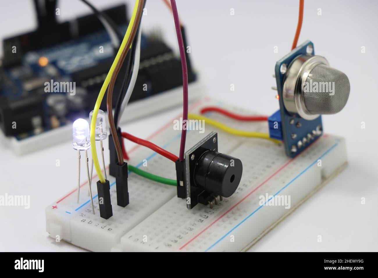 Seitenansicht verschiedener elektronischer Komponenten auf einer Breadboard-Schaltung mit Mikrocontroller im Hintergrund, die das Konzept des Prototyping zeigt Stockfoto