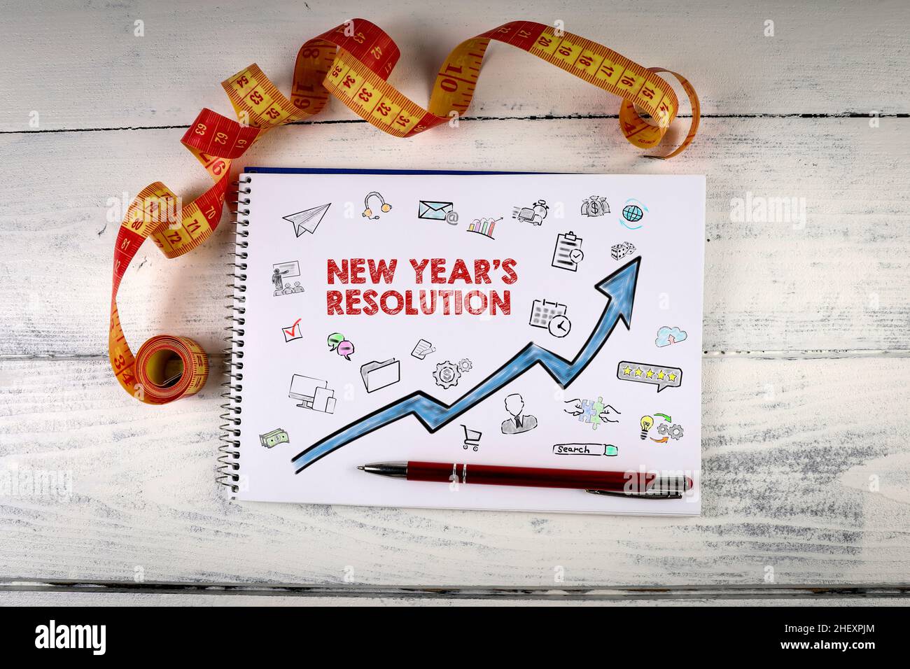 Neujahrsauflösung. Notizbuch und Maßband auf einem Holzhintergrund. Stockfoto