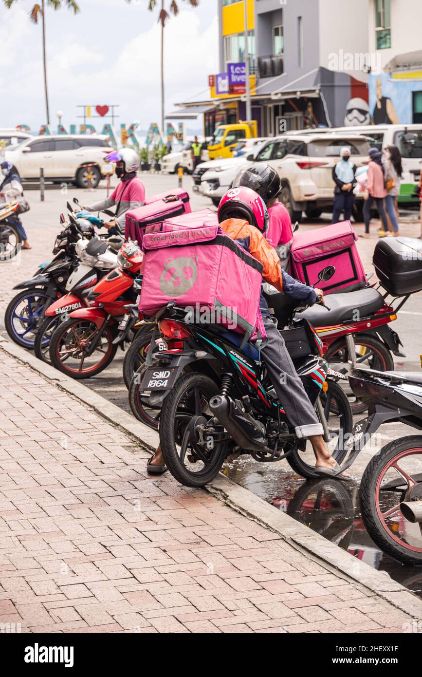 Sandakan, Malaysia - 06. Januar 2022: Food Delivery Rider in Sabah. Food Panda und Grab Fahrer sind immer noch am meisten beschäftigt. Fahrer schiebt sein Fahrrad auf das We Stockfoto