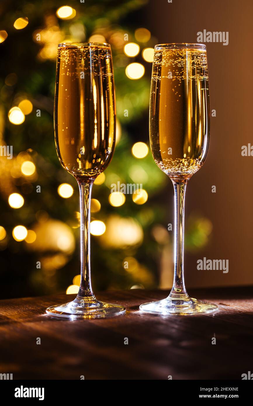 Zwei Gläser Champagner mit weihnachtlichen festlichen Lichtern vor verschwommenem Hintergrund. Feierlaune und Nahaufnahme Stockfoto