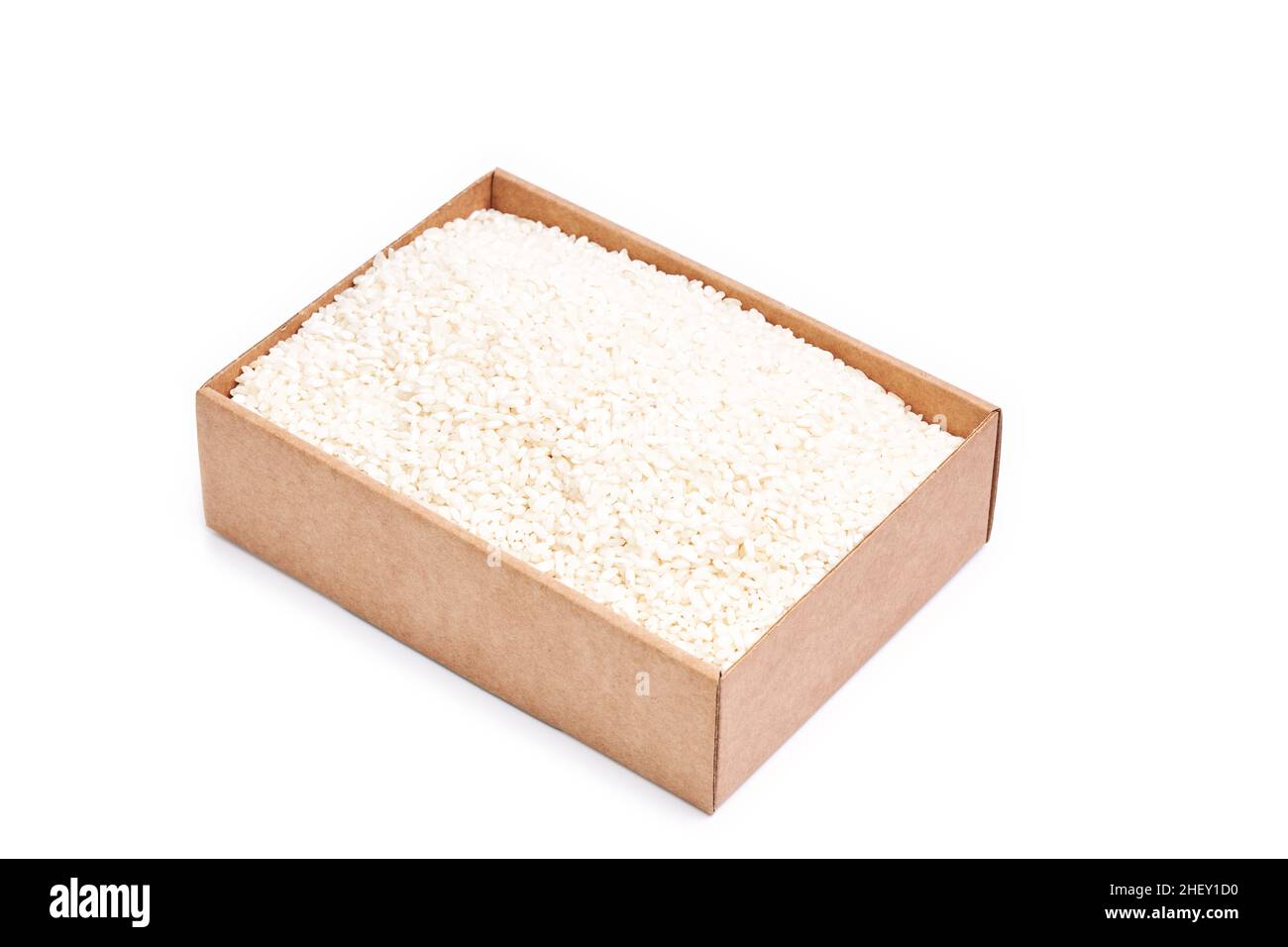 Karton gefüllt mit weißen Reiskörnern auf weißem Hintergrund. Orientalisches und gesundes Essen Stockfoto