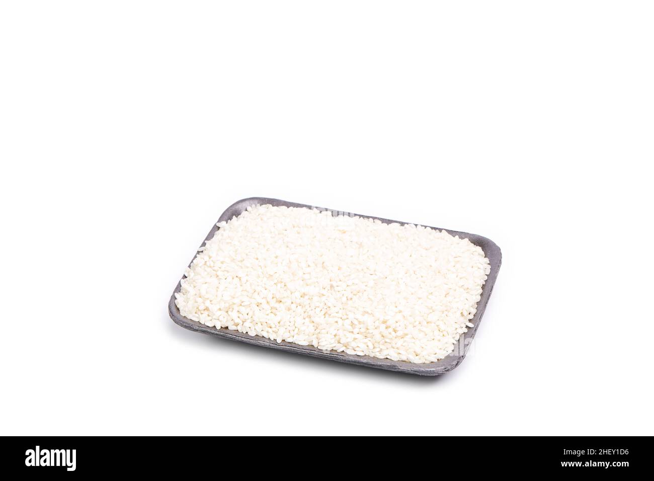 Weiße Reiskörner auf einem Tablett auf weißem Hintergrund. Orientalisches und gesundes Essen Stockfoto