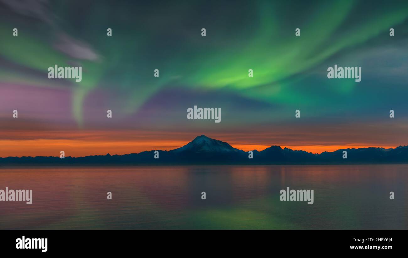 Wunderschöne Alaska-Landschaft bei Sonnenuntergang des Vulkans Mount Redoubt und der Bergkette am Cook Inlet mit den Nordlichtern am Himmel und Spiegelung Stockfoto