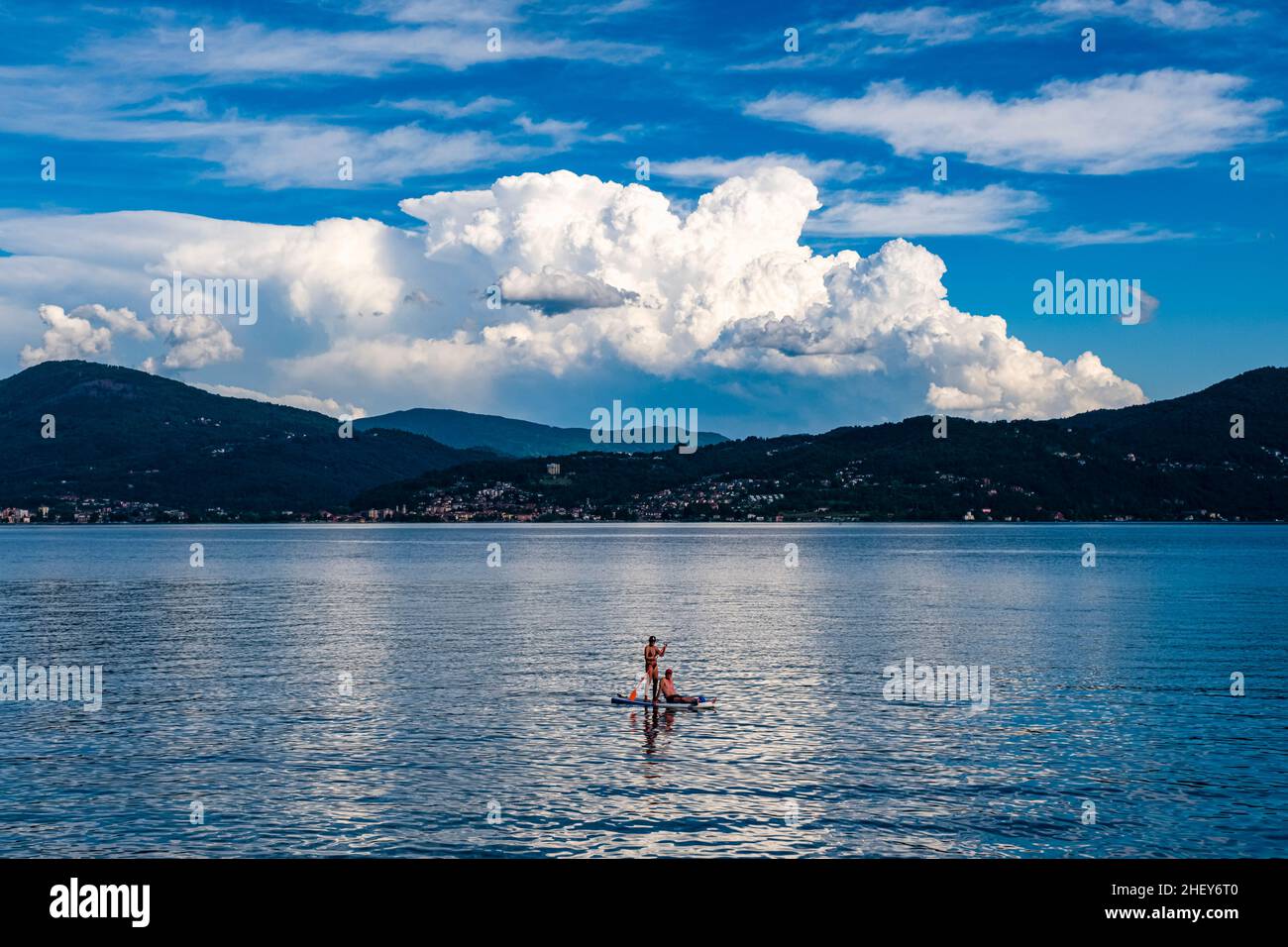 Eine Frau, begleitet von einem Mann, der auf dem Brett sitzt, paddelnd auf dem Lago Maggiore. Stockfoto