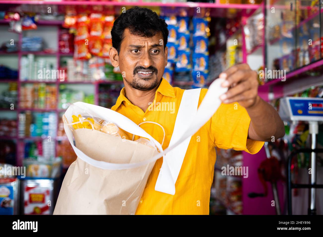 Schockierte Kunden in Kirana oder im Lebensmittelgeschäft, nachdem sie den Eingang der Lebensmittelrechnung gesehen hatten - Konzept der Inflation, steigender Preise und Konsumdenken. Stockfoto