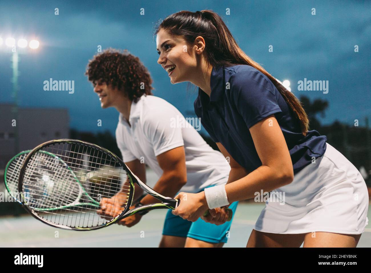 Tennis Sport People Konzept. Gemischter Doppelspieler trifft Tennisball mit Partner steht in der Nähe des Netzes Stockfoto