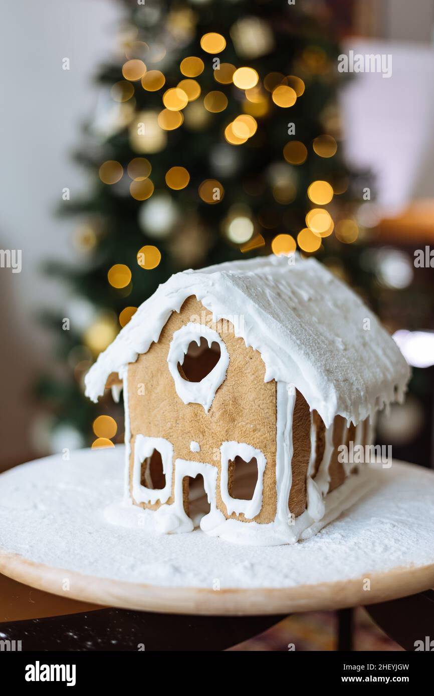 Weihnachtshaus aus Ingwerkekse mit Ingwer Mann draußen in Weihnachtsstimmung mit Baum im Hintergrund dekoriert Stockfoto