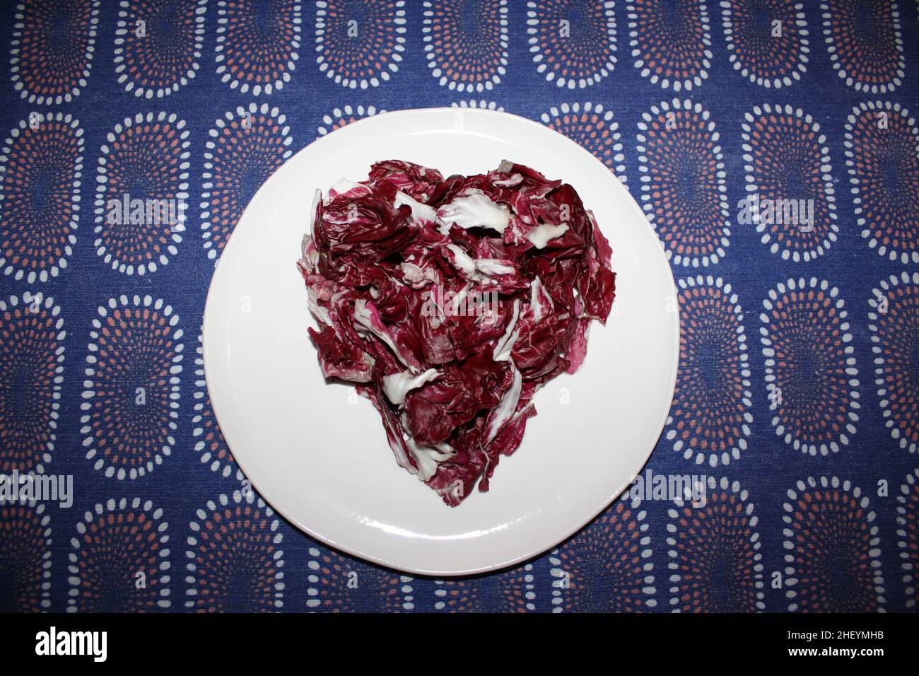 Ein violettes Herz aus italienischem Radicchio auf einem weißen Gericht Stockfoto