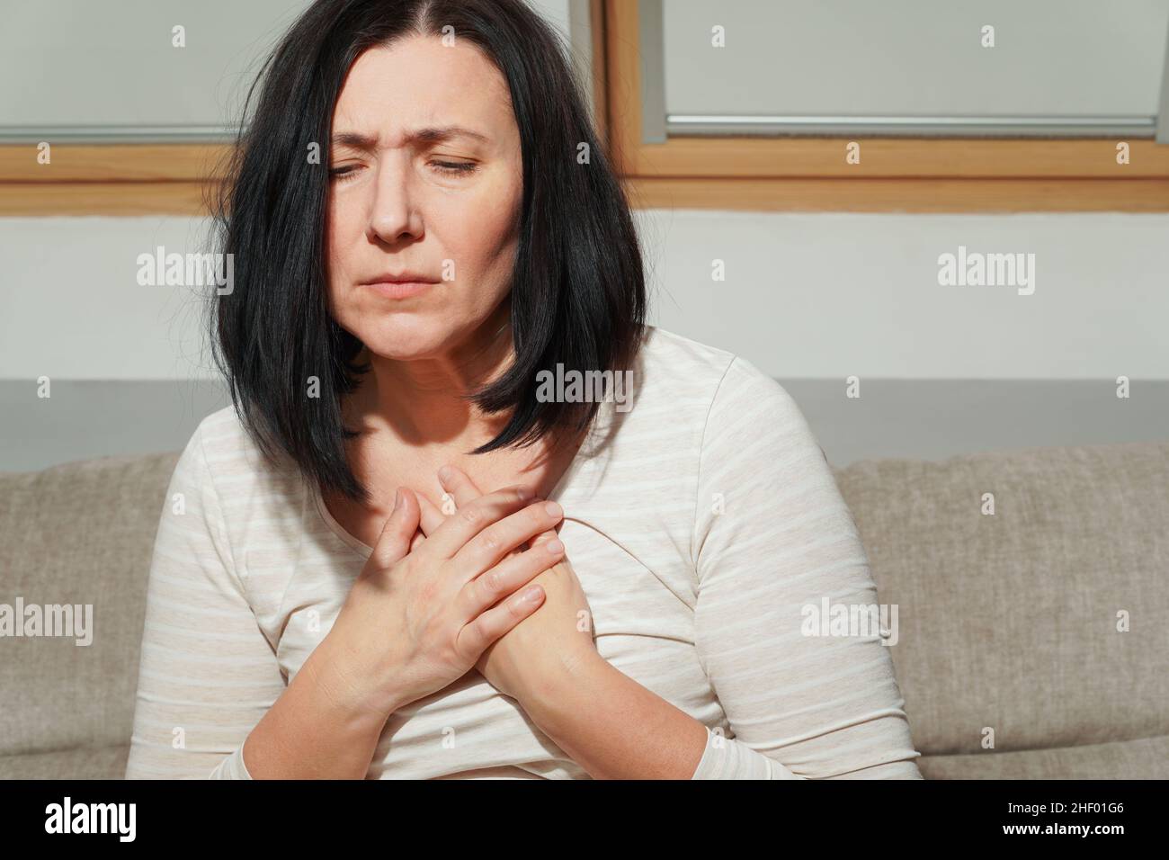 Ältere Frau mittleren Alters mit einem Herzinfarkt. Frau mit Brustschmerzen. Gesundheitsfürsorge und kardiologisches Konzept. Stockfoto