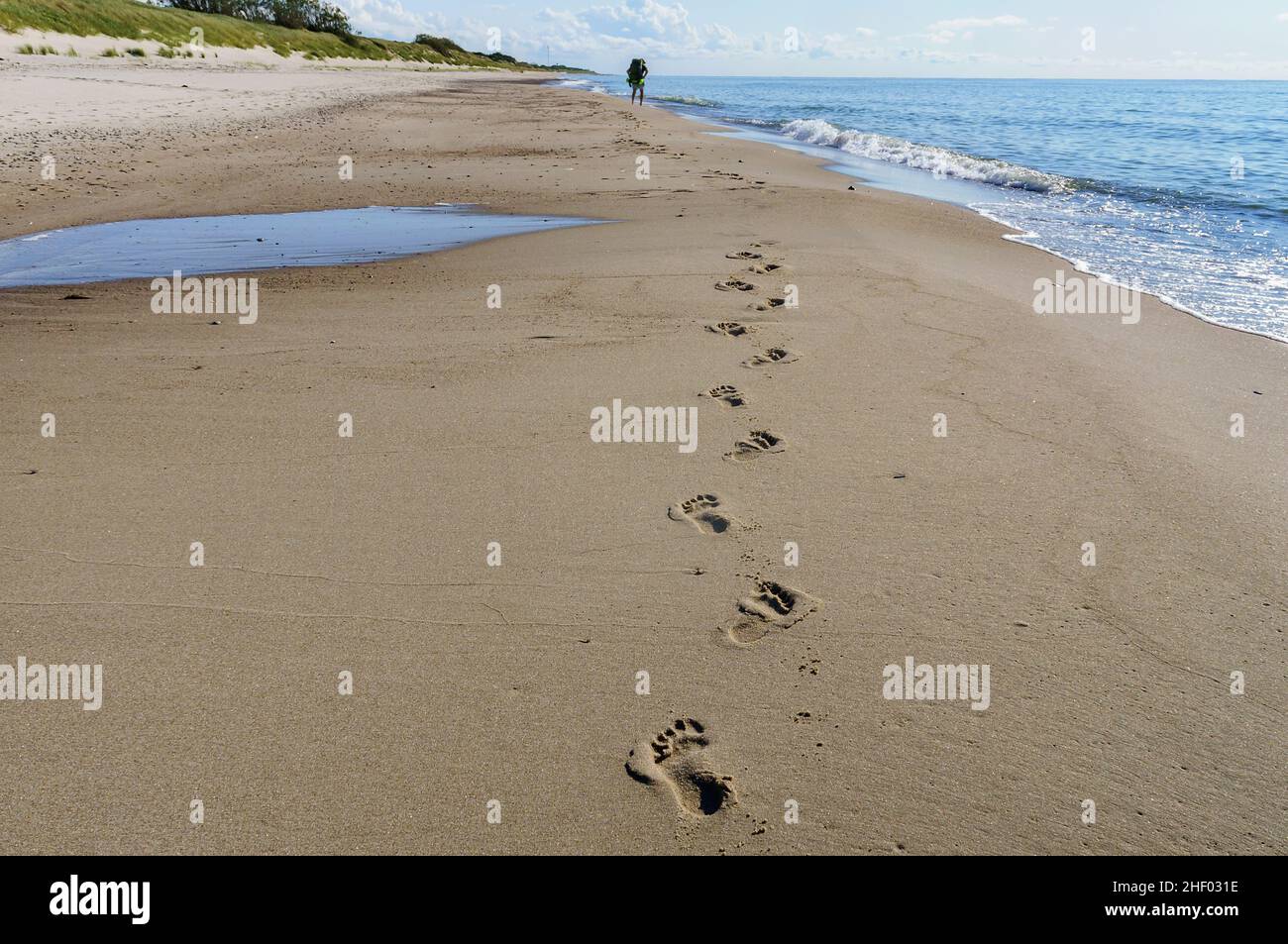 Fußabdrücke auf dem Meersand. Ostseeküste und ruhiges Meer. Wandern Sie am Meer entlang. Stockfoto