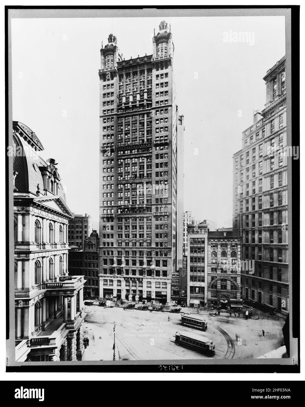 Blick auf das Park Row Building, Manhattan, New York City, im Jahr 1912, zeigt Autos, die auf der Straße geparkt sind und Trolleys. Stockfoto