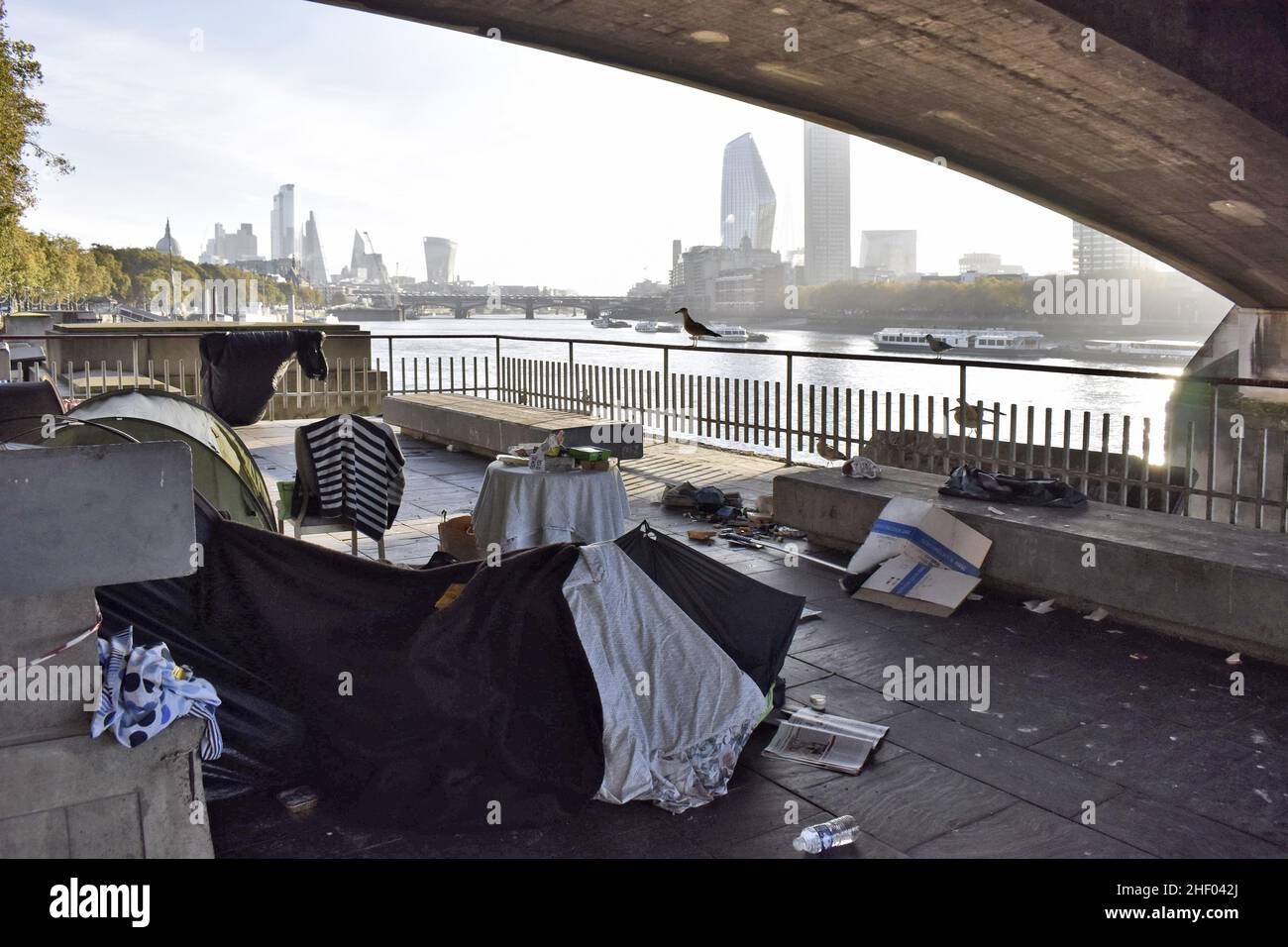 Obdachlose Zelte am Ufer der Themse unter der Waterloo-Brücke und moderne Wolkenkratzer im Hintergrund, London UK. Stockfoto